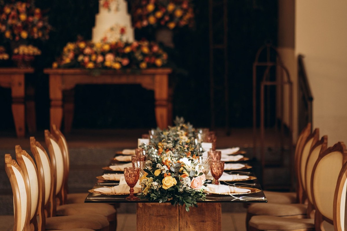 Festlich gedeckte Hochzeitstafel in dunklem Saal mit warmem Licht